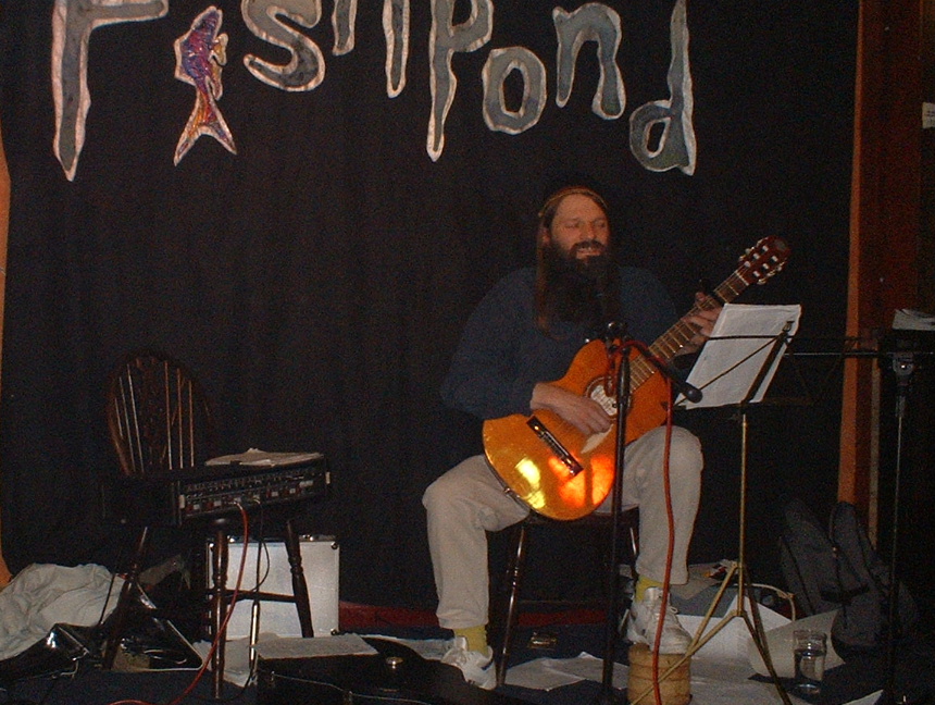 guitarist alan robinson performing at the fishpond matlock bath in front of a backdrop decoratyed with a fish